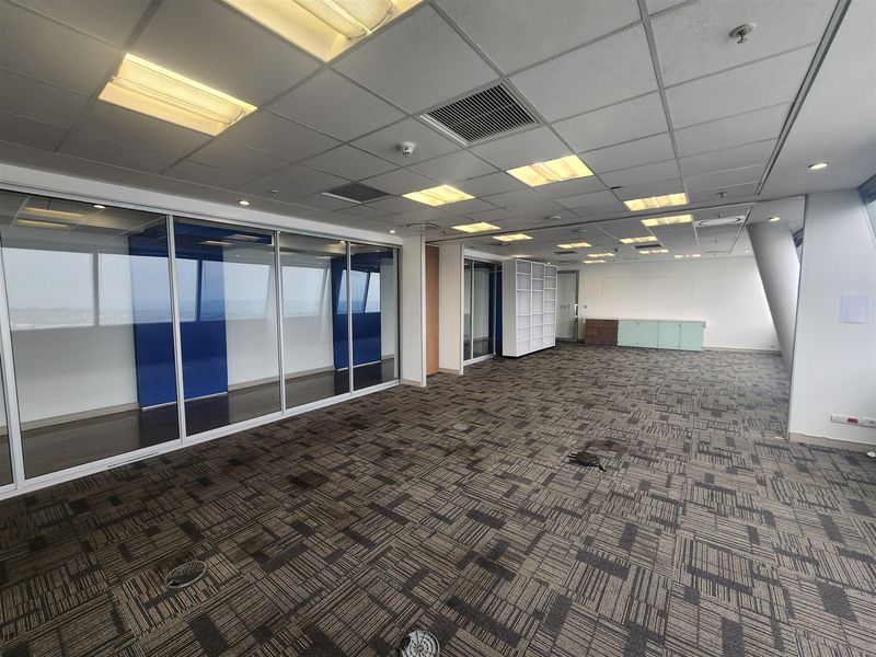Spacious open-plan office area featuring glass partitions, suspended ceilings with recessed lighting, and durable carpet tiles throughout.