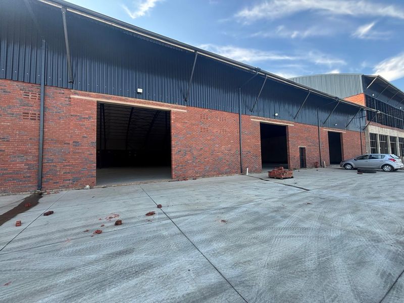 Industrial warehouse exterior featuring a face brick facade, corrugated metal cladding, and a large concrete hardstand area with multiple access points.