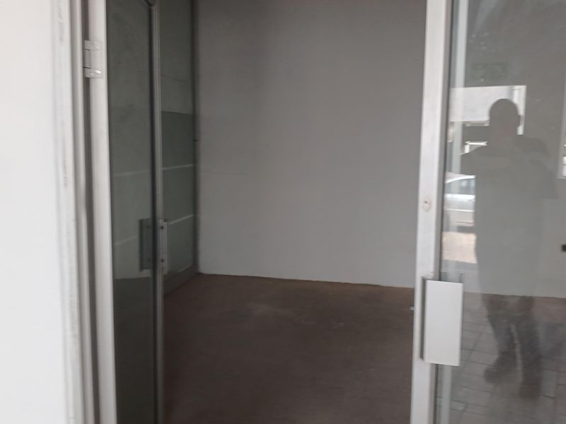 An empty office space featuring aluminium framed glass doors and glass partitioning, suitable for a professional workspace or commercial use.