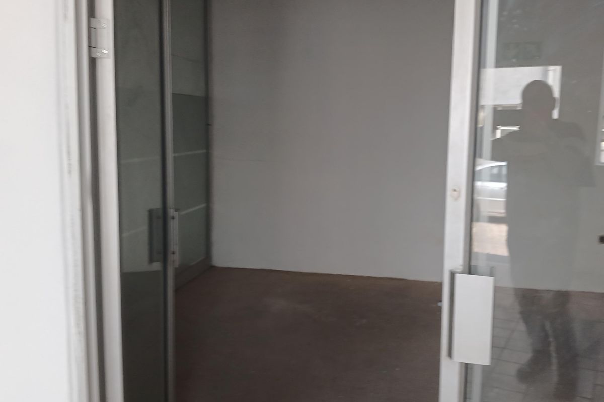 An empty office space featuring aluminium framed glass doors and glass partitioning, suitable for a professional workspace or commercial use.