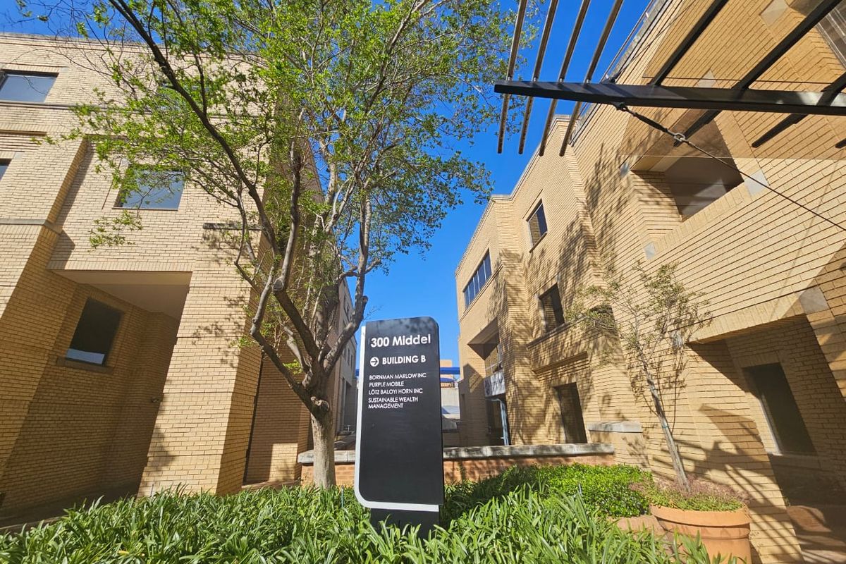 Exterior view of the 300 Middel Building B office complex, featuring brick facade architecture, professional signage, and landscaped garden areas.