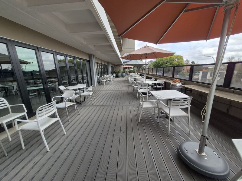 Spacious outdoor balcony featuring composite decking, glass balustrades, and large bi-fold doors providing seamless access to the interior office space.
