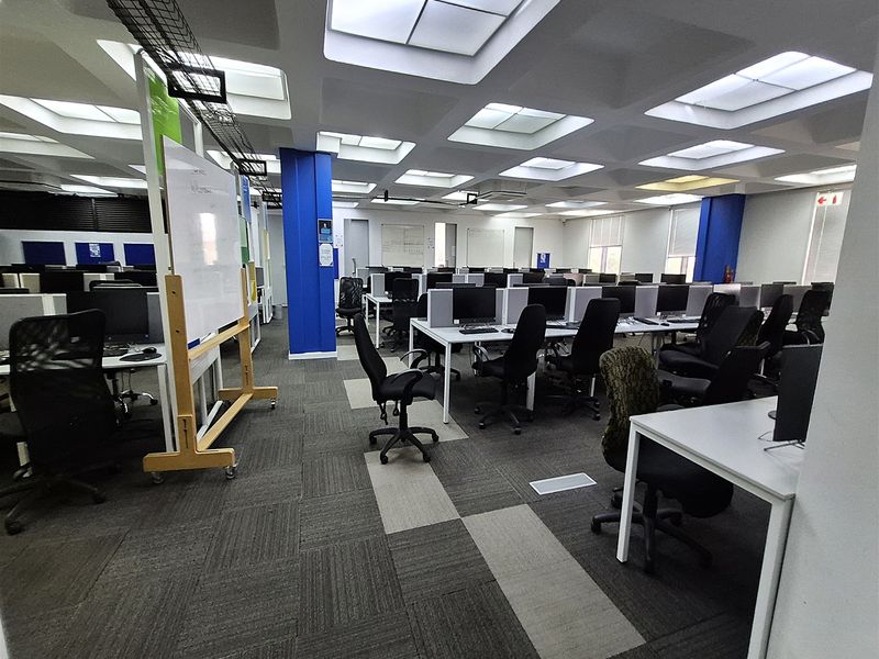 Spacious open-plan office area featuring a coffered ceiling with recessed lighting, carpet tile flooring, and integrated cable management systems.