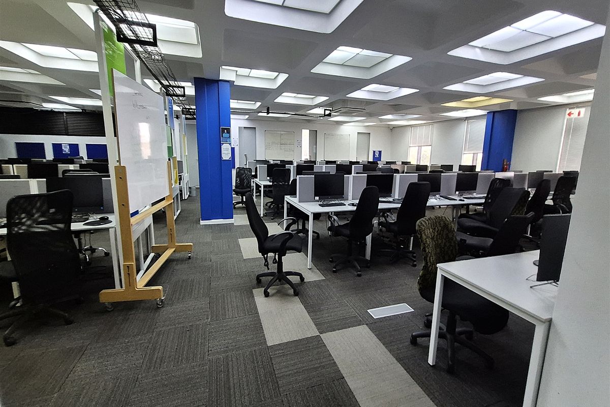 Spacious open-plan office area featuring a coffered ceiling with recessed lighting, carpet tile flooring, and integrated cable management systems.