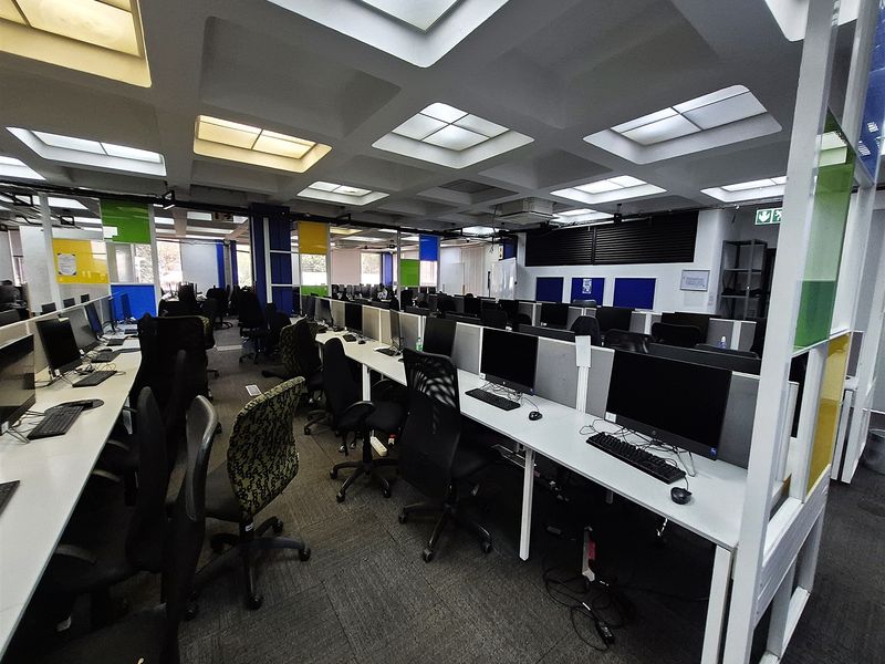A spacious open-plan office area featuring a distinctive coffered ceiling with recessed lighting, carpeted flooring, and integrated workstation partitioning.