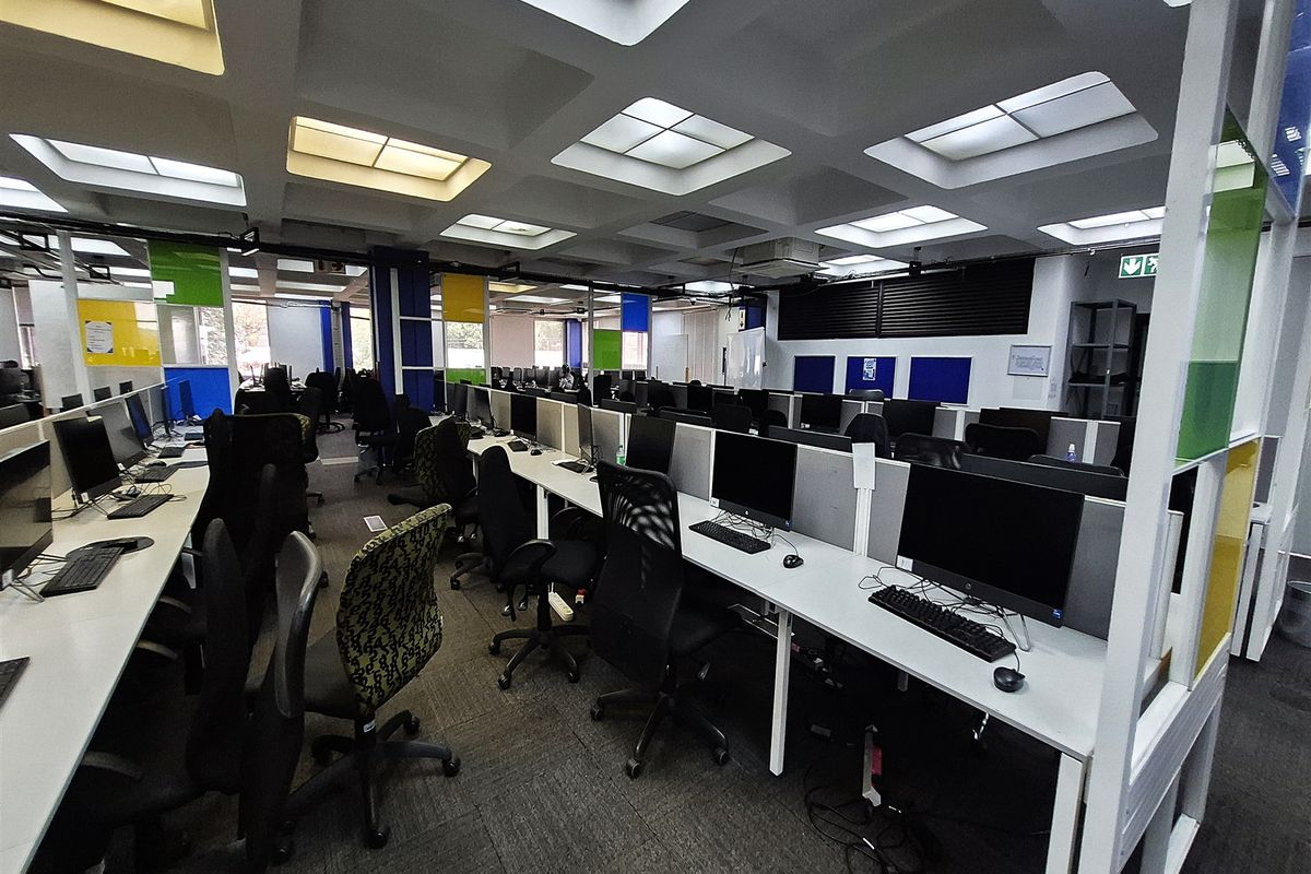 A spacious open-plan office area featuring a distinctive coffered ceiling with recessed lighting, carpeted flooring, and integrated workstation partitioning.