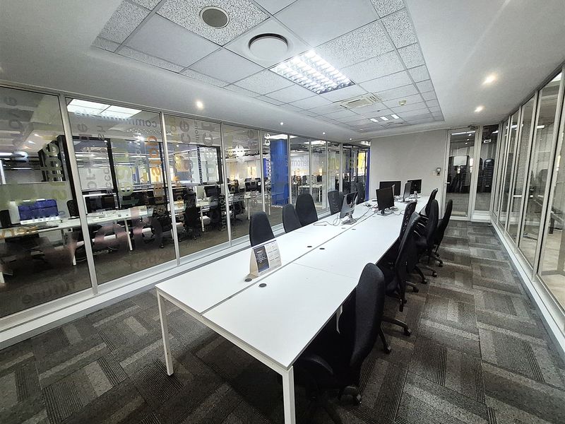 Modern office space featuring glass partition walls, suspended ceilings with recessed lighting, and durable carpet tiles, providing a professional and collaborative work environment.