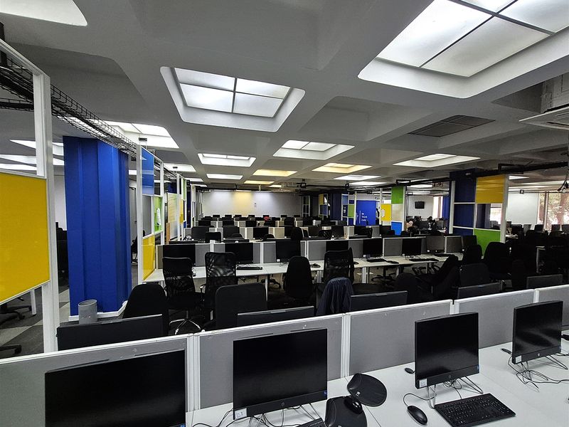 A large open-plan office space featuring modular workstations, integrated cable management, and recessed ceiling lighting throughout the professional work environment.