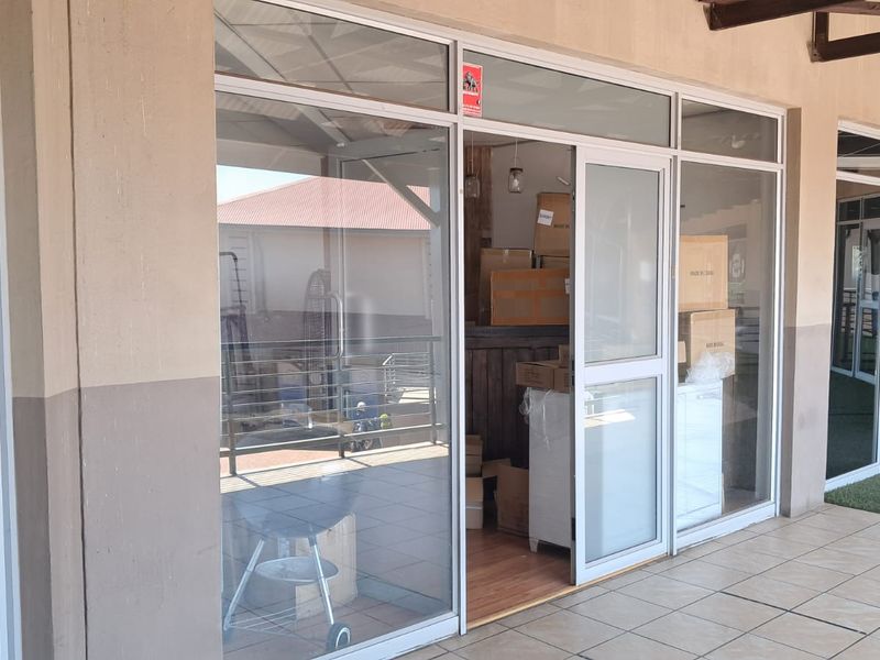 Exterior view of an office unit featuring aluminium-framed glass sliding doors and a covered tiled walkway.