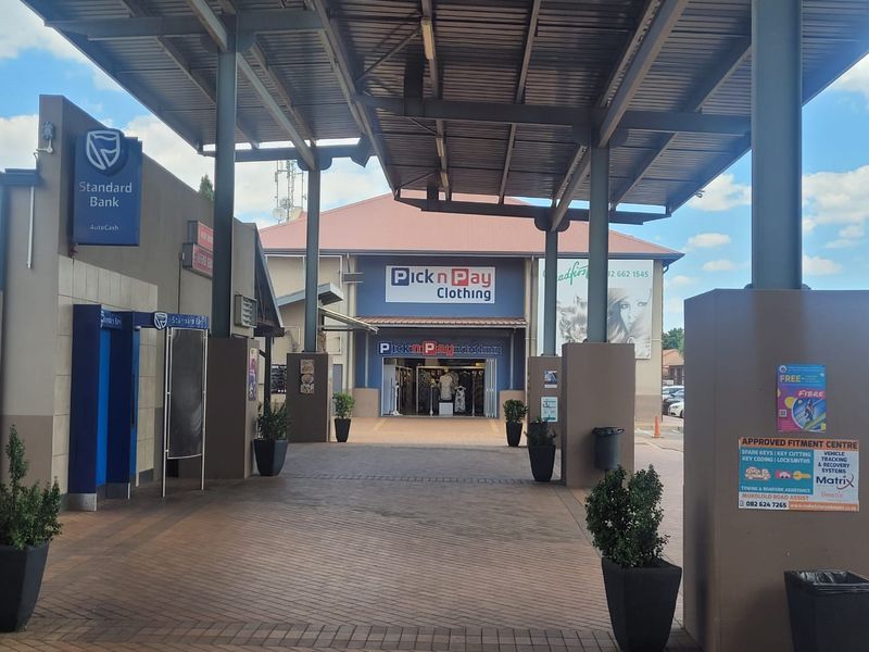A well-maintained commercial office and retail complex entrance featuring a covered walkway, paved access area, and prominent signage for established tenants.
