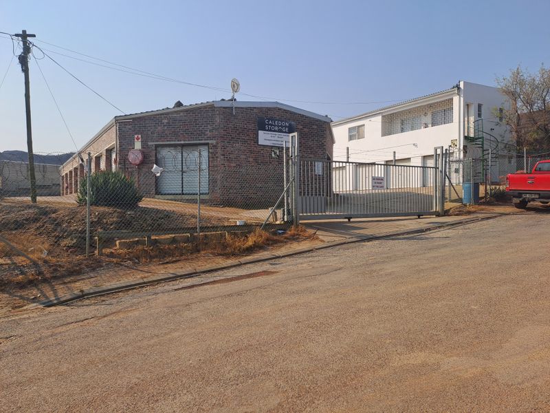 Front view of an industrial storage facility featuring secure gated access, brick construction, and perimeter security fencing.
