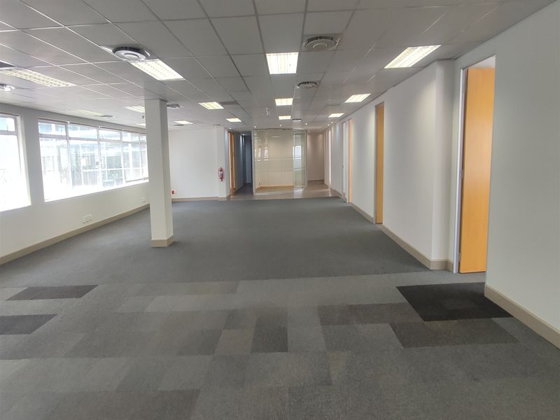 Spacious open-plan office area featuring suspended ceilings, recessed lighting, carpet tiles, and central air conditioning, offering a clean and professional workspace.