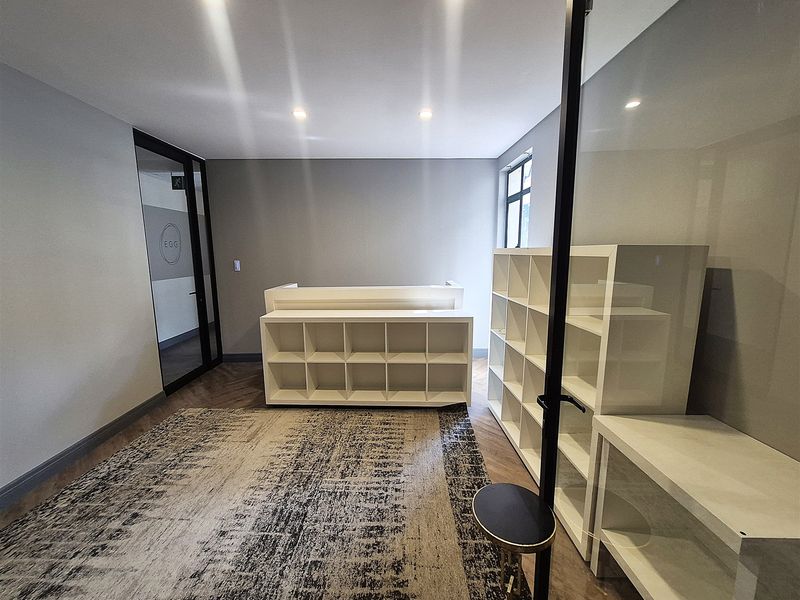 A modern office space featuring herringbone flooring, recessed lighting, and a glass partition wall, providing a clean and professional work environment.