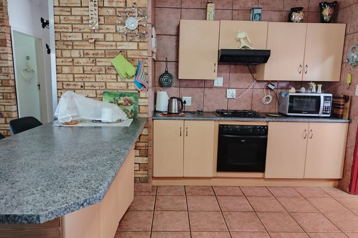 A functional kitchen featuring built-in cabinetry, a gas hob with extractor, built-in oven, and a breakfast bar with granite countertops.