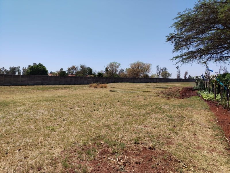 A large, open garden area on the farm property, featuring a long precast concrete boundary wall and natural grass terrain.