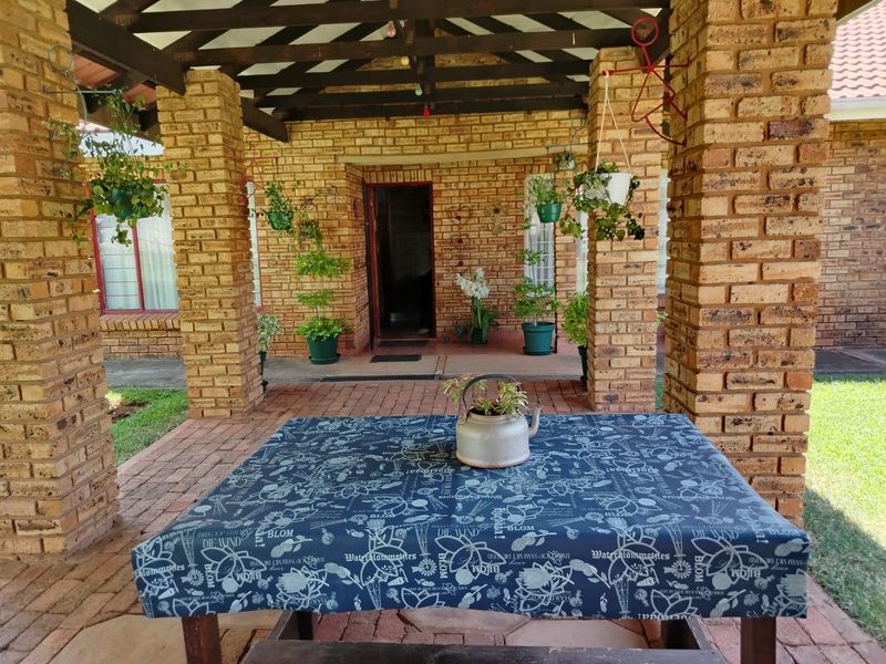 A covered outdoor patio featuring rustic face brick pillars, exposed timber beams, and brick paving, providing a charming entrance to the home.