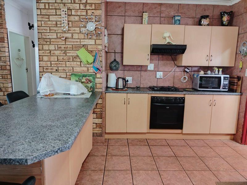 A functional kitchen featuring built-in cabinetry, a gas hob with extractor, built-in oven, and a breakfast bar with granite countertops.