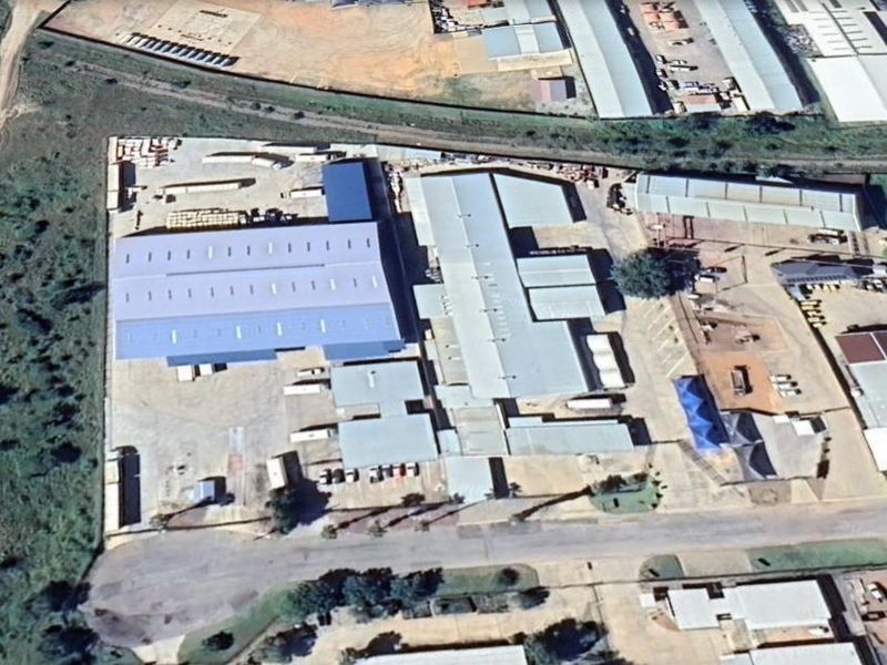 Aerial view of an industrial property featuring multiple warehouse structures, extensive paved yard space, and perimeter access.
