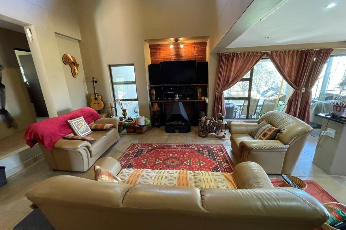 Spacious living room featuring a vaulted ceiling, tiled flooring, and a central freestanding fireplace with direct access to the outdoor patio area.