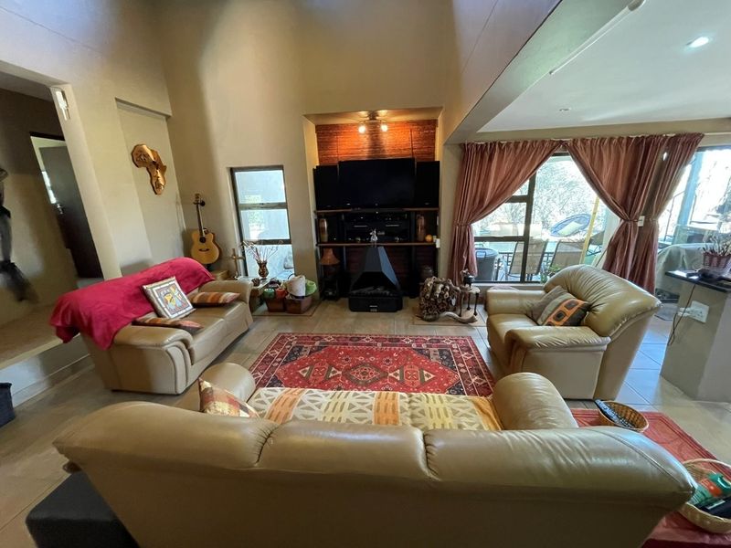 Spacious living room featuring a vaulted ceiling, tiled flooring, and a central freestanding fireplace with direct access to the outdoor patio area.