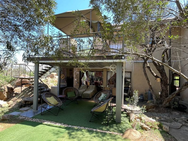 A covered ground-floor patio area featuring artificial turf, leading to an upper-level balcony with metal railings and an external staircase.