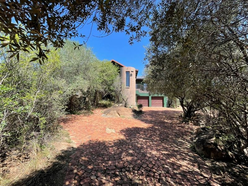 Front view of a small holding property featuring a cobblestone driveway, double garage, and a distinctive turret architectural element.