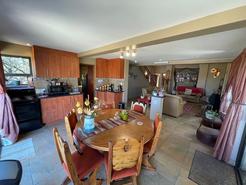 Spacious open-plan living area featuring a kitchen with wooden cabinetry, dining space, and a staircase leading to the upper level.