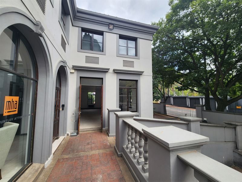 Front entrance view of a professional office building featuring a brick paved walkway, classic architectural archways, and a decorative balustrade.