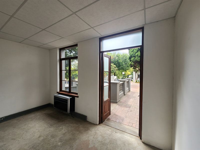 An empty office space featuring a suspended ceiling, concrete flooring, and direct access to an outdoor patio area.