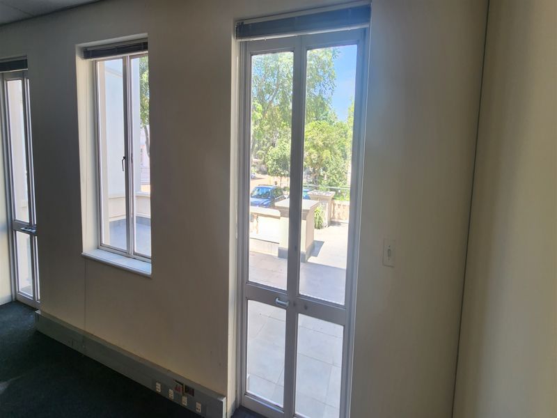 Empty office space featuring carpet flooring, electrical trunking, and direct access to an outdoor balcony area through an aluminium glass door.