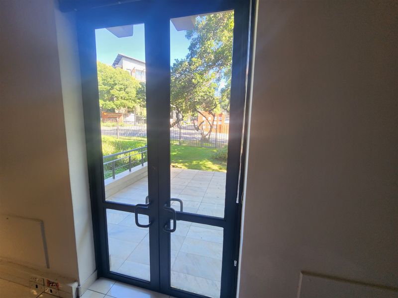 Interior view looking through double glass doors onto a paved patio area with garden access.