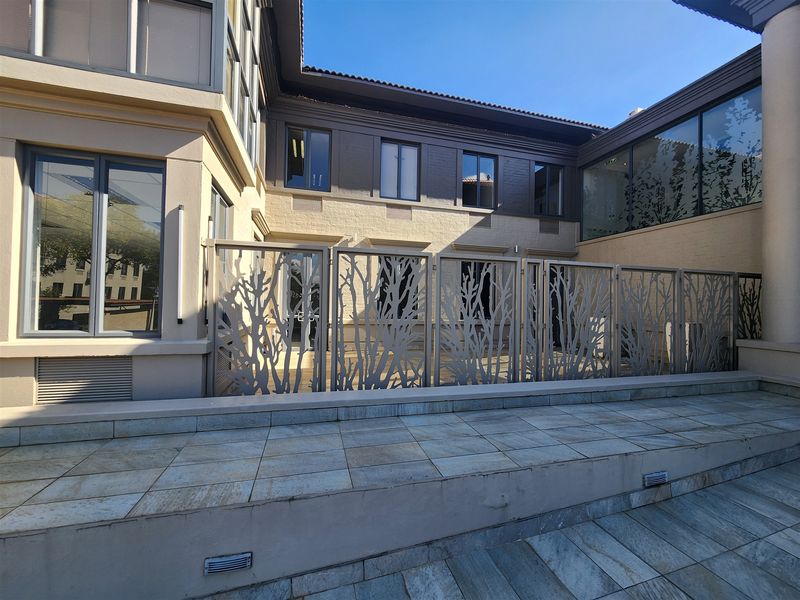 A well-maintained rear courtyard area featuring stone paving, decorative laser-cut metal privacy screens, and modern aluminium-framed windows.