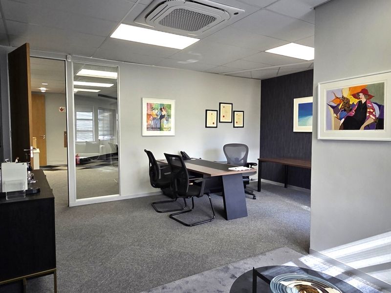 A professional office space featuring a suspended ceiling with integrated air conditioning, glass partitioning, and carpeted flooring.