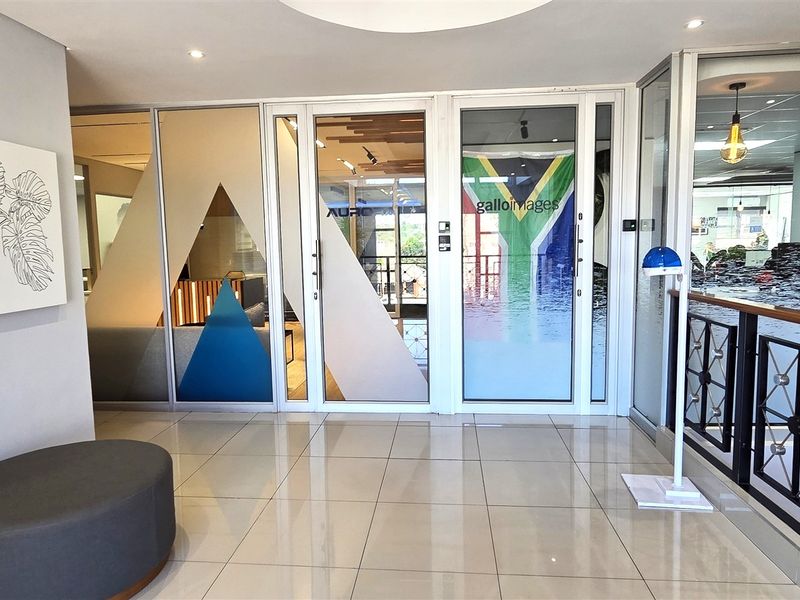 Modern office entrance lobby featuring tiled flooring, glass partition walls, and a decorative metal balustrade, creating a professional and welcoming reception area.