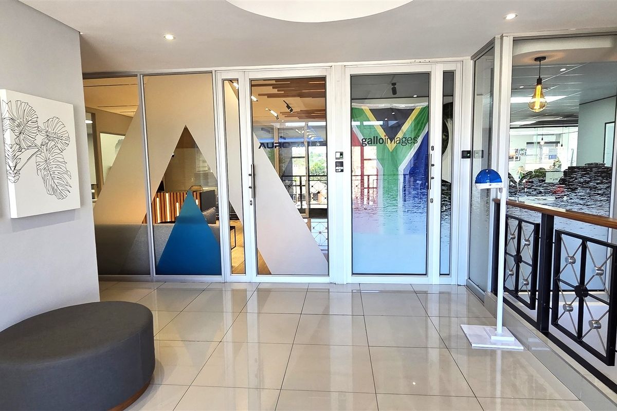 Modern office entrance lobby featuring tiled flooring, glass partition walls, and a decorative metal balustrade, creating a professional and welcoming reception area.