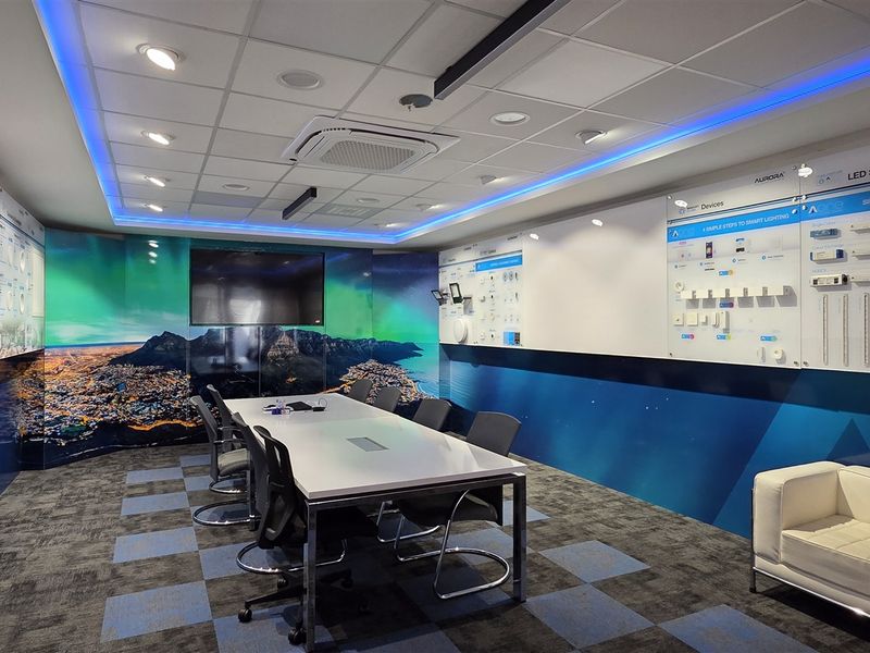Modern professional office boardroom featuring a suspended ceiling with integrated LED lighting, cassette air conditioning, and wall-mounted product display panels.