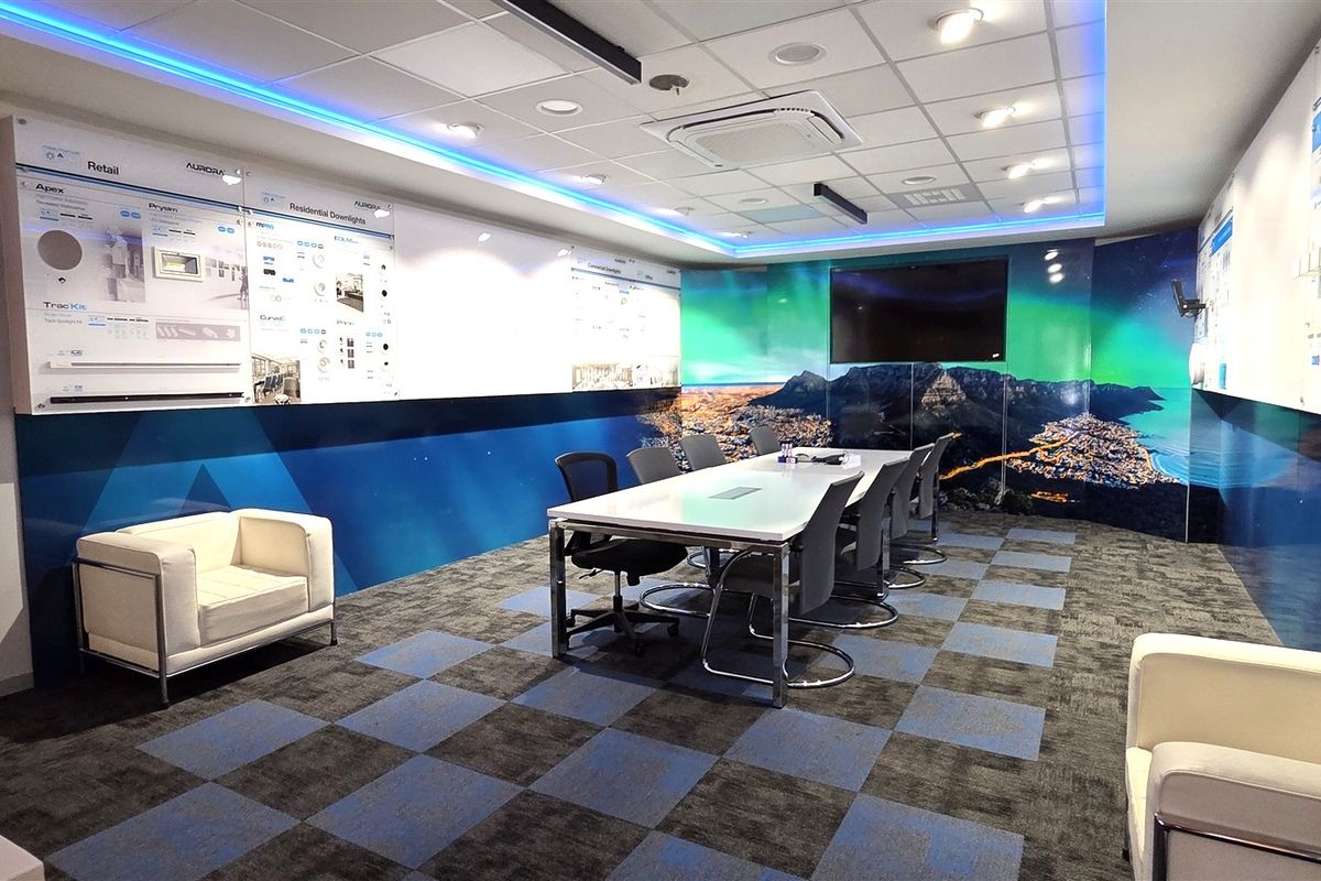 Modern office boardroom featuring a suspended ceiling with integrated LED lighting, cassette air conditioning, and professional wall-mounted product display panels.