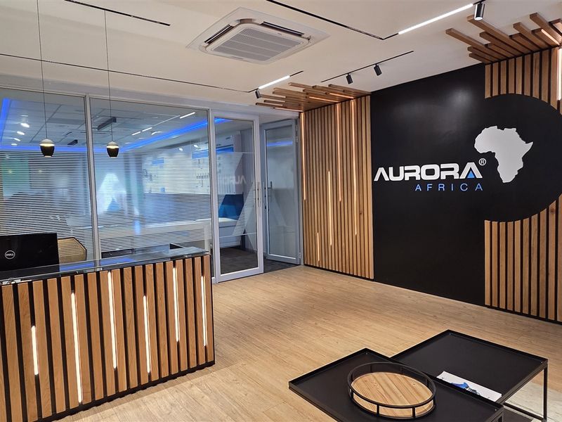 Modern office reception area featuring a custom wood-slat desk, integrated LED accent lighting, and professional glass-partitioned office entry.