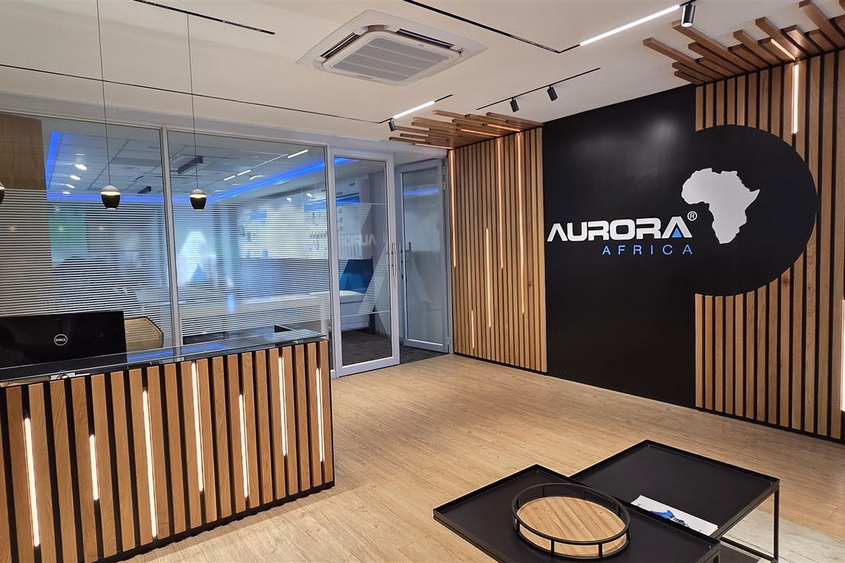Modern office reception area featuring a custom wood-slat desk, integrated LED accent lighting, and professional glass-partitioned office entry.