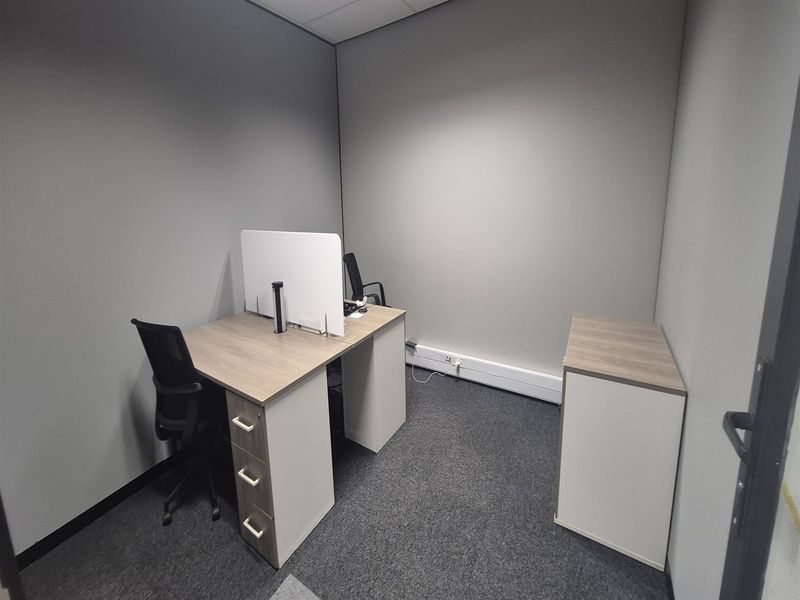 A compact private office space featuring grey carpet flooring, neutral wall finishes, and integrated electrical trunking for connectivity.