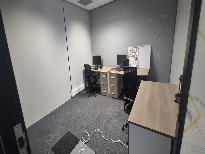 A functional office space featuring carpeted flooring, neutral walls, and a suspended ceiling, suitable for a professional work environment.