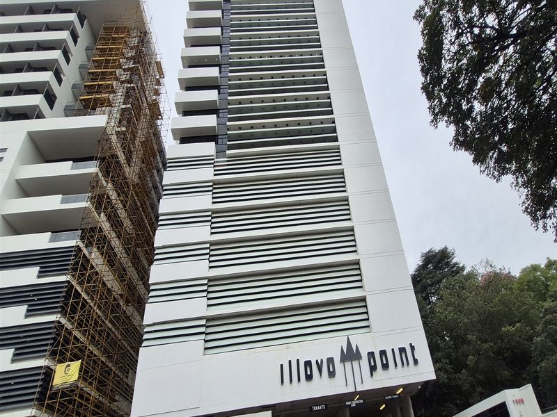 Modern high-rise office building facade featuring clean architectural lines, integrated balconies, and prominent signage at the street-level entrance.
