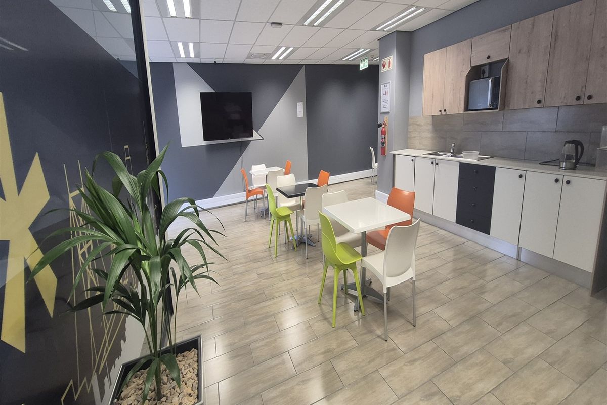 Modern office kitchenette featuring built-in cabinetry, integrated microwave, stainless steel sink, and durable tiled flooring in a clean, professional workspace environment.