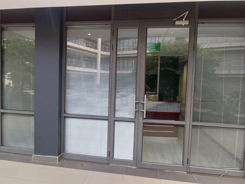 Commercial office entrance featuring modern aluminium-framed glass doors and partitioning with integrated blinds, providing a professional and transparent facade.