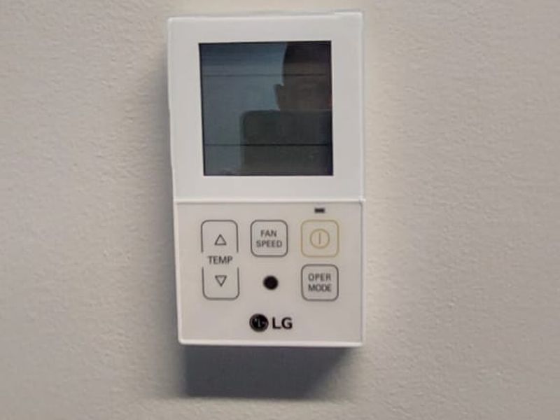 A wall-mounted LG air conditioning control panel for climate management.
