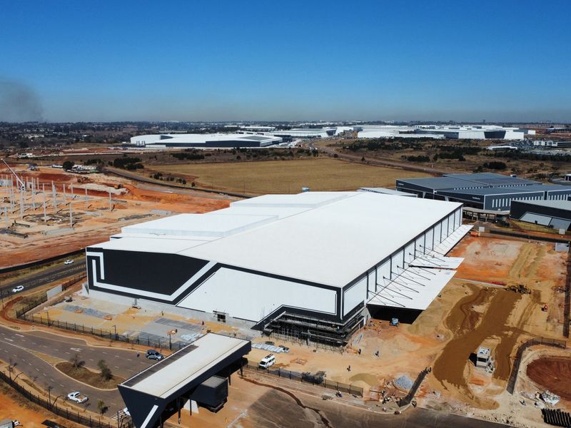 Aerial view of a modern industrial warehouse facility featuring large loading bays, a security gatehouse, and extensive surrounding infrastructure in a business park setting.