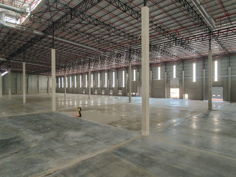 Expansive industrial warehouse space featuring high ceilings with exposed steel trusses, polished concrete flooring, and integrated fire suppression and ventilation systems.