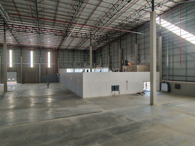 Spacious industrial warehouse featuring high ceilings with exposed steel trusses, polished concrete flooring, and integrated fire sprinkler systems.