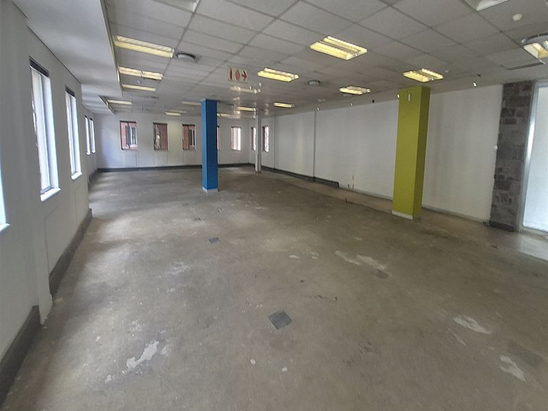 A large, open-plan office space featuring a suspended ceiling, recessed lighting, and exposed concrete flooring, ready for custom fit-out.