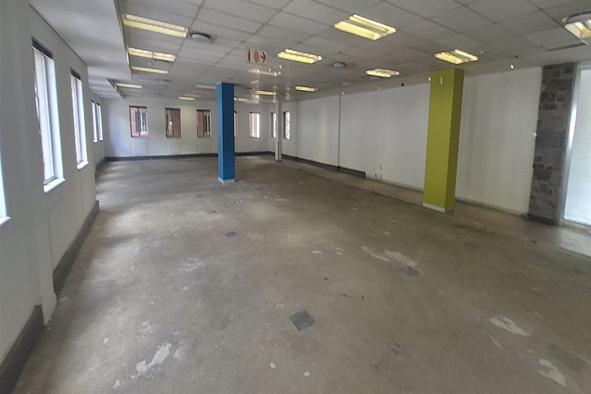 A large, open-plan office space featuring a suspended ceiling, recessed lighting, and exposed concrete flooring, ready for custom fit-out.